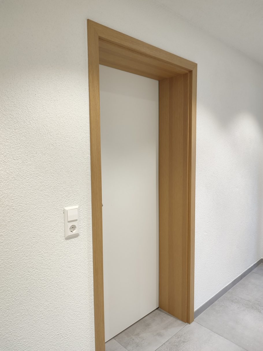 Türe Weiße Tür mit Holzrahmen in einem modernen Innenraum.
